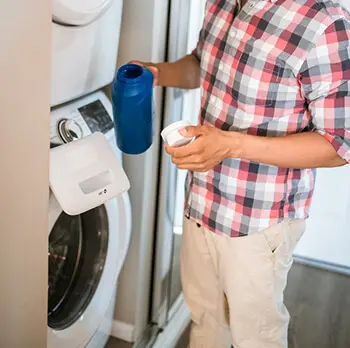 person adding vinegar to washing machine