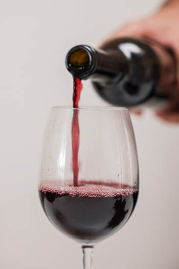 pouring red wine on a glass